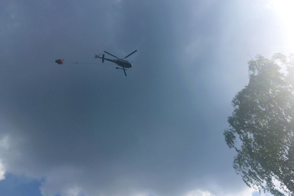 Med stor precision släpper helikopterförarna miljoner lite vatten över skogsbranden i Kosta.
