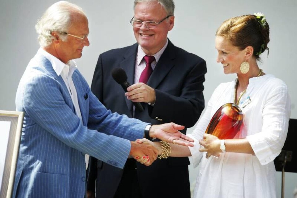Kung Carl XVI Gustaf och Anna Barkevall konstaterar att de precis blivit kollegor. Kungen utsås till Årets ölänning 1996. Konferencieren Odd Zschiedrich övervakar prisutdelningen.
