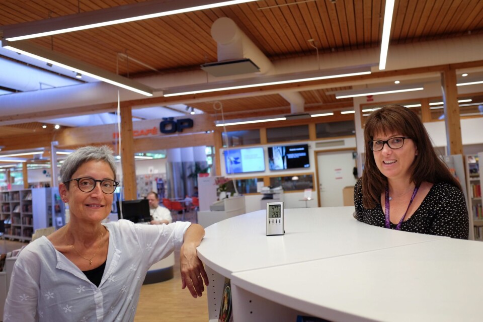Bibliotekarierna Ingrid Borg och Anna Sonesson på sin arbetsplats, där termometern just denna stund visar 28 grader. ”Vi påminner ofta varandra om att dricka mycket och ibland ta pauser för att gå ut och svalka av oss.”