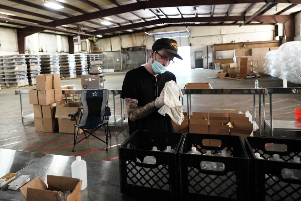 En man torkar av en flaska med handsprit vid en produktionsanläggning i Texas.