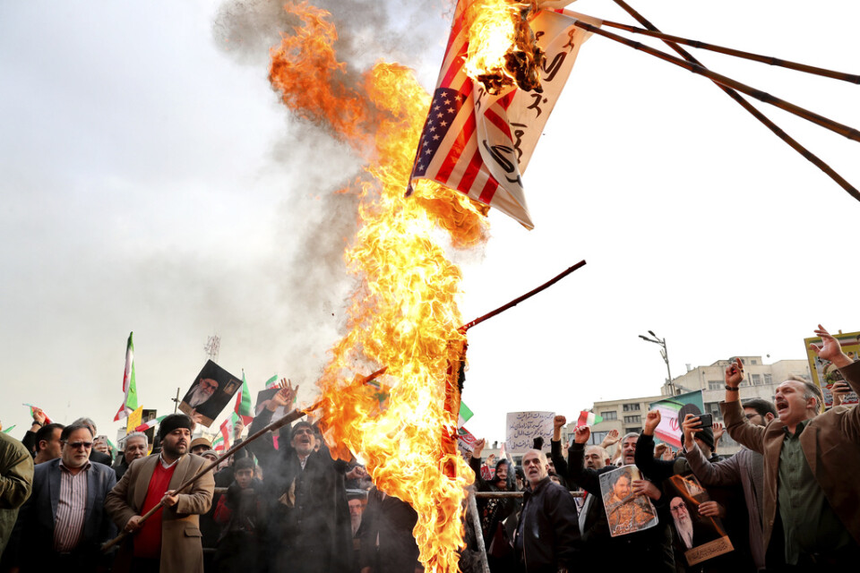 Demonstranter bränner en avbildning av den amerikanska flaggan.