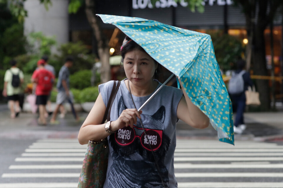 En kvinna i Taipei kämpar med sitt paraply i de starka vindarna.