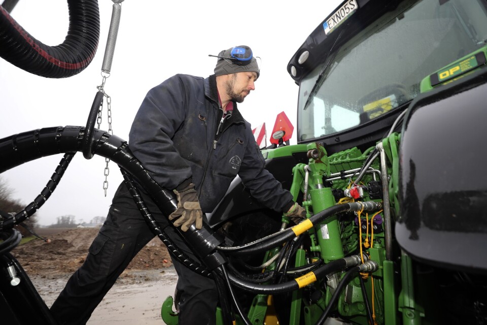 Martin Andersson kopplar hydraulslangar mellan traktorn och gödseltunnan.