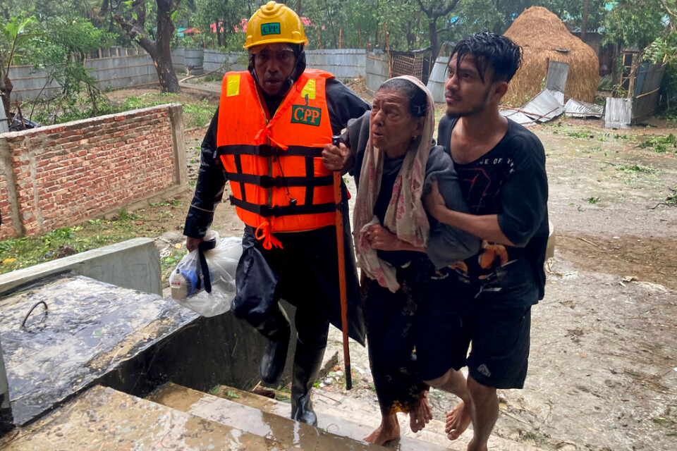 Räddningsarbetare hjälper en kvinna att söka skydd i Teknaf nära Cox's Bazar.