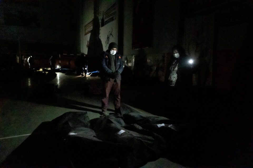 I den strömlösa gymnastiksalen i Kahramanmaras bryts mörkret endast av flackande mobiltelefonlampor. På bilden tar ett par farväl av sin dotter, hennes man och deras treåriga dotter, vars kroppar ligger insvepta på golvet.
