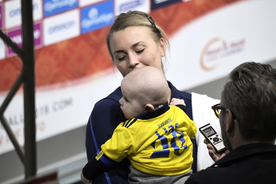 Sveriges spelmotor Iaabelle Gulldén möter journalisterna med sonen Lias i famnen efter den tredje raka VM-segern. Värdnationen Japan besegrades med 34–26.