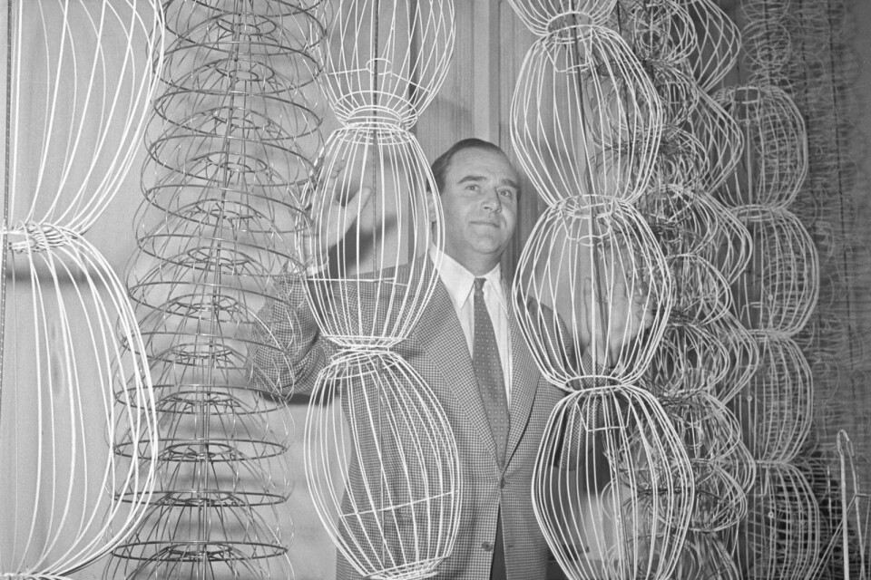Hans Bergström står mitt i Ateljé Lyktans lager av lampskärmar. Mängden bildar ett vackert grafiskt mönster, som en installation. Vad arbetade Hans med? Hur såg produktionsleden ut? Året var 1952.