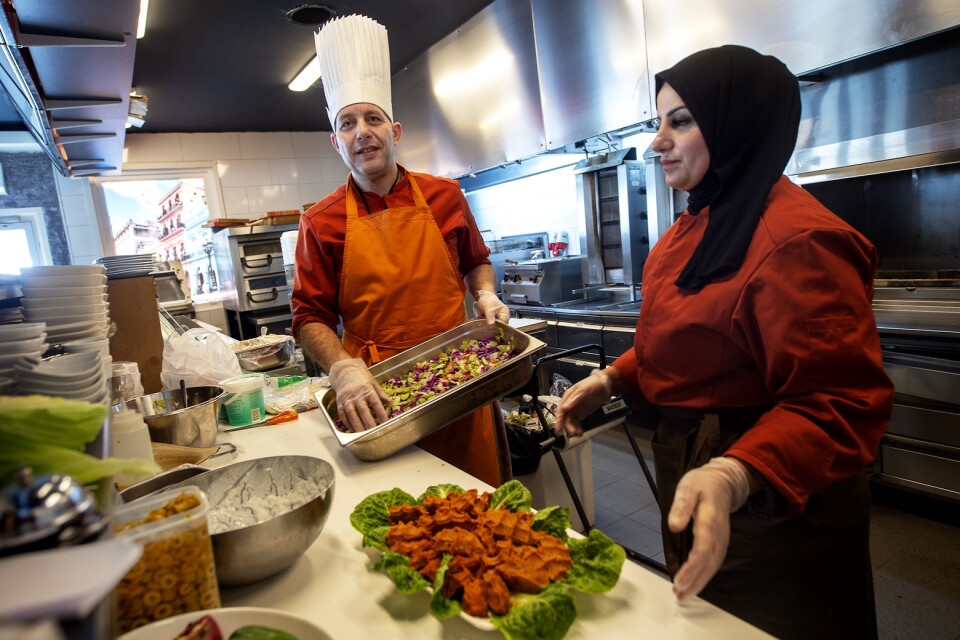 Kocken Mohammed Aljamos och hans assistent, Asmaa Alasmi, serverar en tallrik med syrisk kibbeh och sallad.