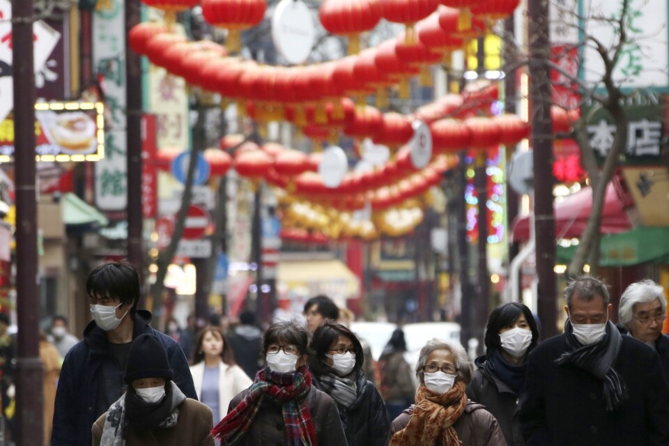 Människor i ansiktsmundering i Chinatown-området i Yokohama, Japan.