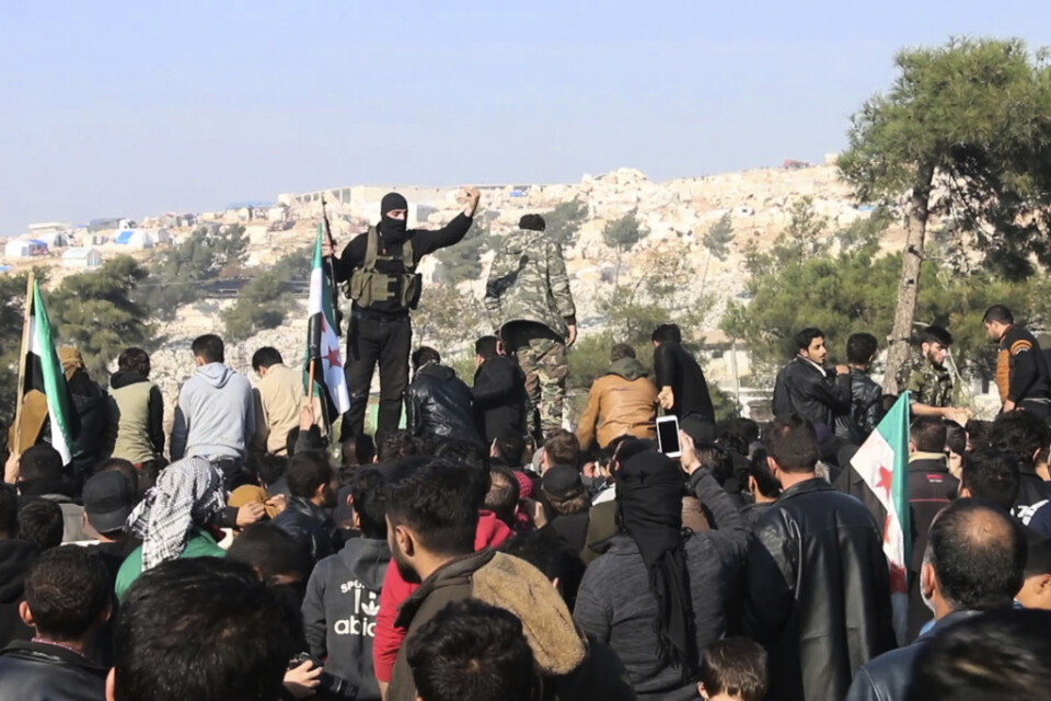 Stridande från jihadistalliansen Hayat Tahrir al-Sham försöker skingra en folkmassa som protesterar mot regeringssidans flyganfall i Idlib. Arkivbild från den 20 december.