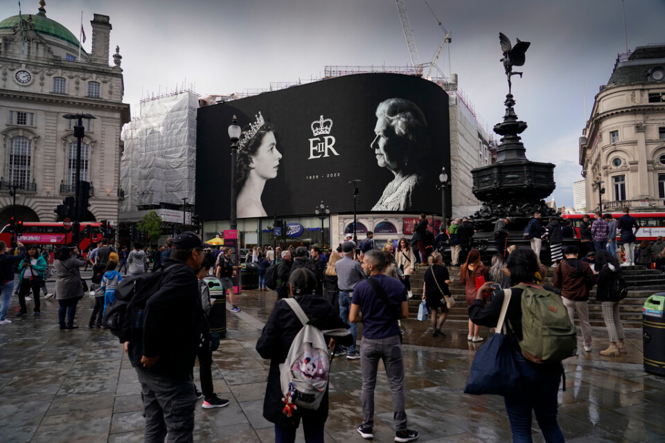 Drottning Elizabeths foto lyser upp en storbildsskärm på ett regnigt Piccadilly Circus i London.