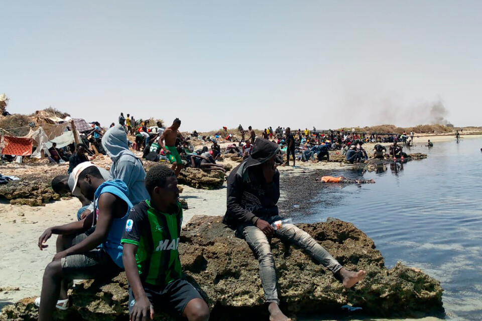 På fotot från den 6 juli som tagits av en migrant från Elfenbenskusten sitter en grupp migranter fast vid en strand nära gränsen mot Libyen.