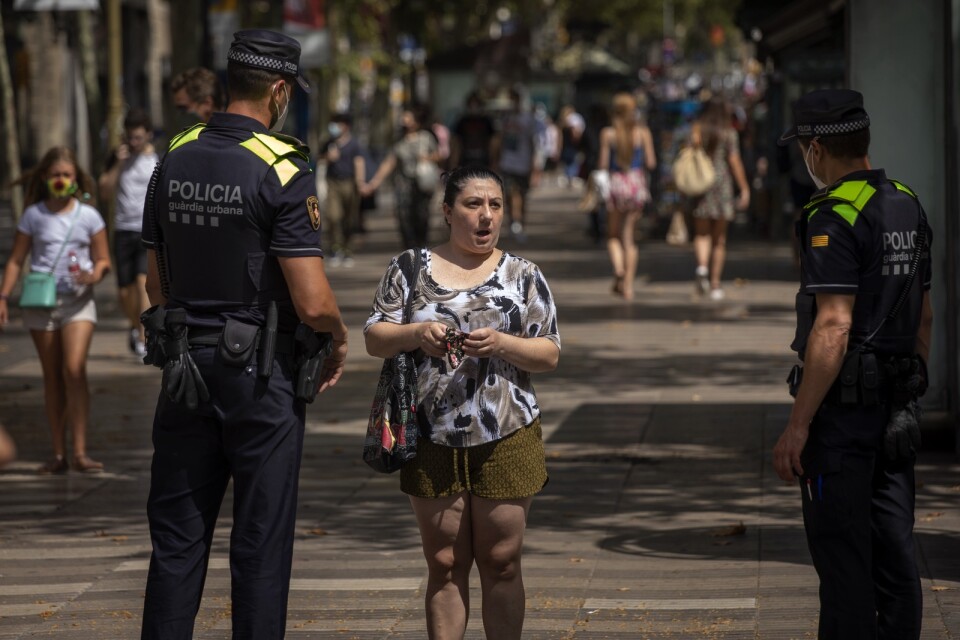 Katalansk polis säger till en kvinna att det är obligatoriskt att bära munskydd. Arkivbild.