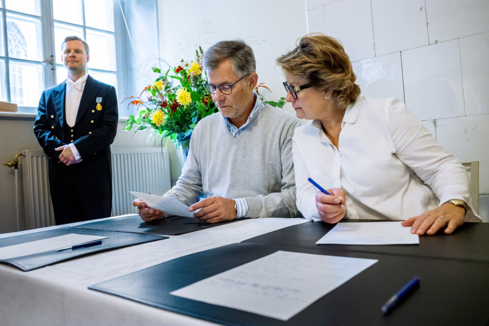 Peter och Hanna Malmström från Stockholm skriver gratulationer till kungen under överinseende av hovlakej Valter Nordkvist.