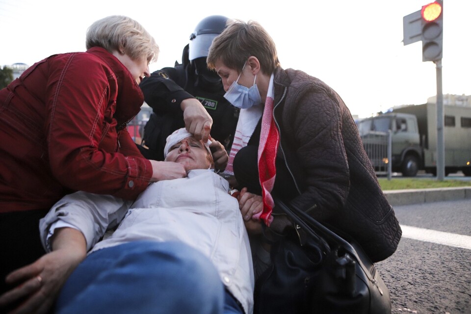 En kvinna som skadades vid demonstrationer i Minsk på onsdagen tas om hand av andra demonstranter.
