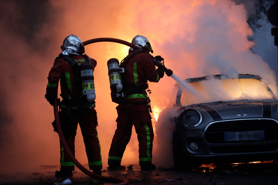 Brandmän försöker släcka en bilbrand nära Paris paradgata Champs-Élysées.