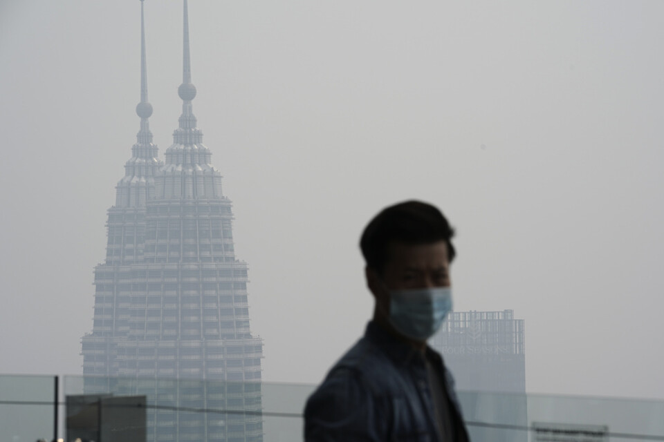En turist i Kuala Lumpur med munskydd som skydd mot röken som väller in från skogsbränderna i grannlandet.