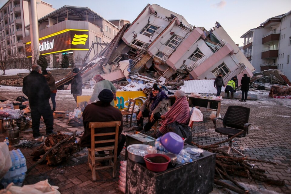 Människor sitter framför förstörda byggnader i Golbasi i södra Turkiet.