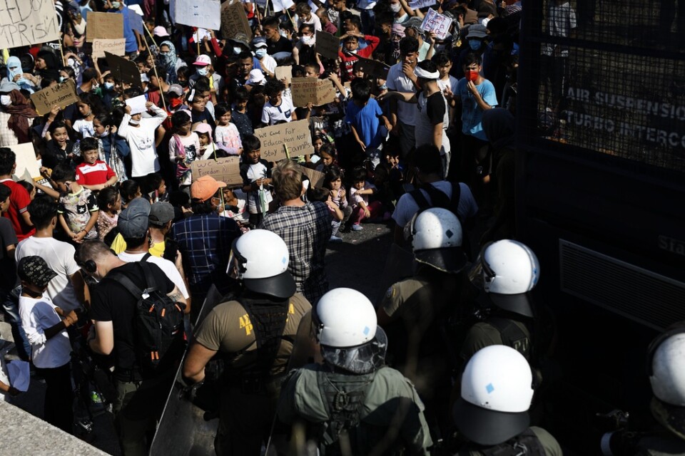 Poliser blockerar en väg nära Mytilene på Lesbos, där migranter protesterar.