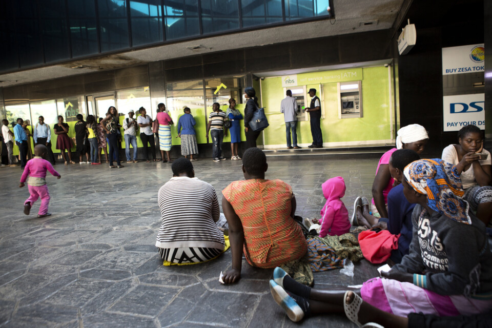 Människor i Zimbabwes huvudstad Harare köar utanför en bankomat, tidigare i år.