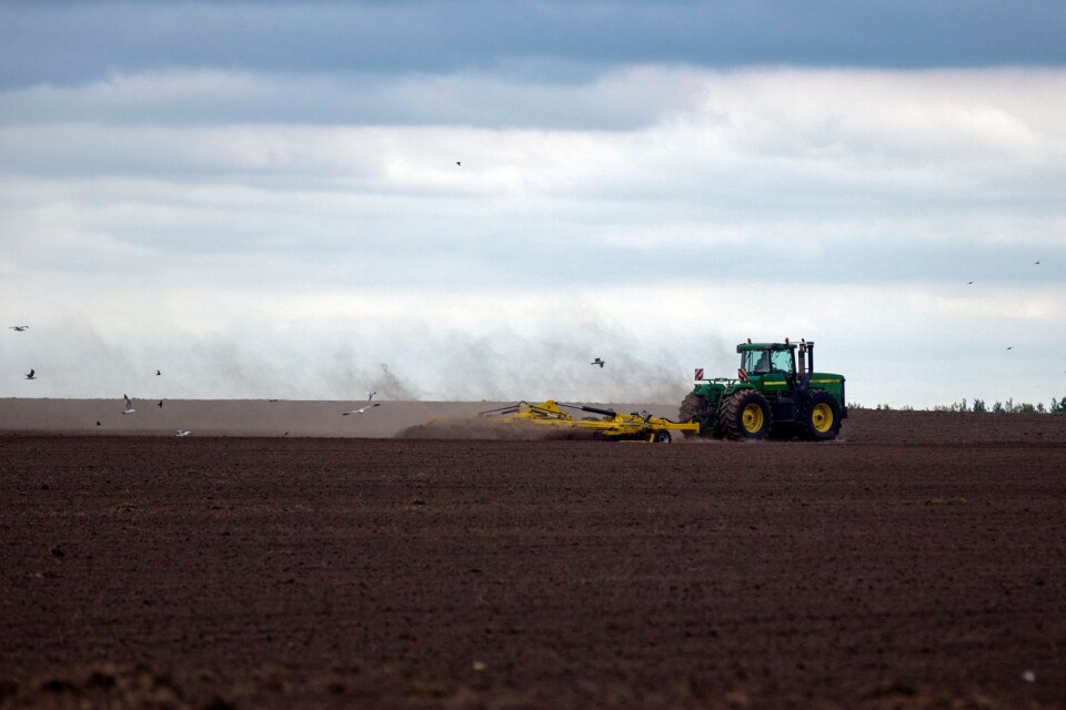 En traktor behandlar den bördiga svarta jorden i Ukraina.