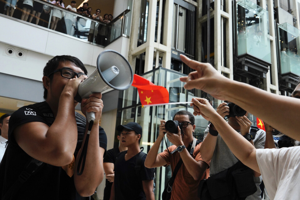 En demonstrant från proteströrelsen försöker göra sin röst hörd framför prokinesiska demonstranter i ett köpcentrum i Hongkong. Bilden togs fredagen den 13 september.