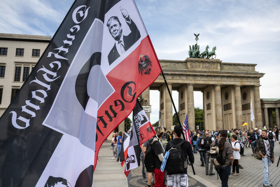 En demonstrant håller det tidigare tyska rikets svart-vit-röda flagga vid en demonstration framför Brandenburger Tor i Berlin, i augusti 2020. Flaggan används av Reichsbürger-rörelsen och just denna pryds också av bland andra Donald Trump. Arkivbild.