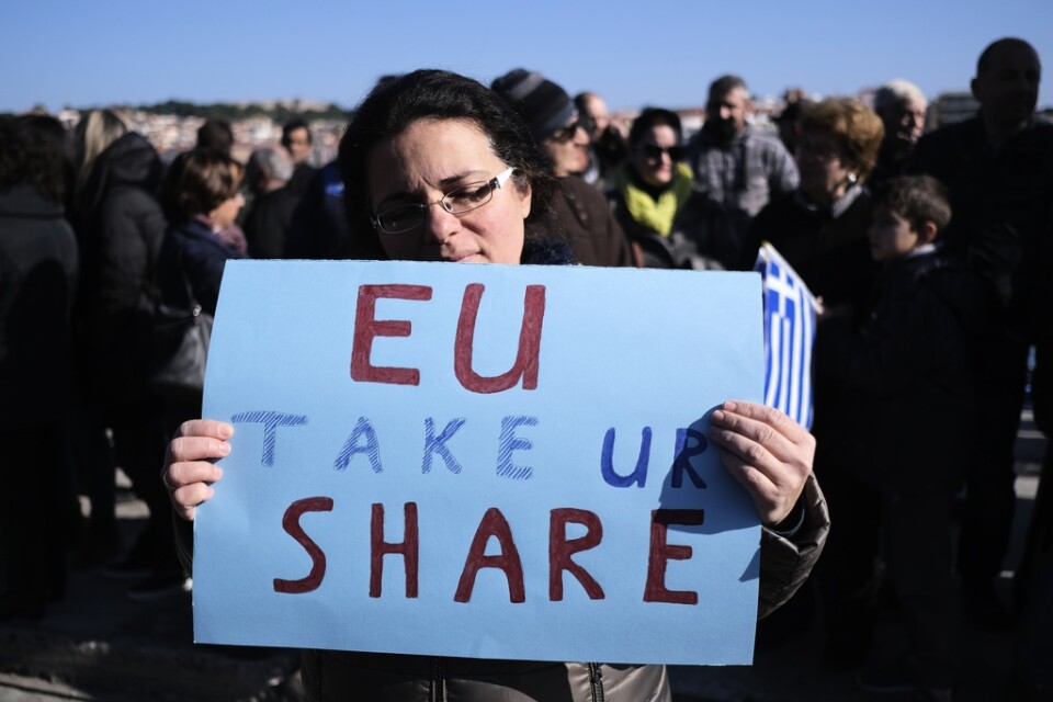 En demonstrant manar EU att ta sitt ansvar under protester på Lesbos mot öns stora flykting- och migrantläger.