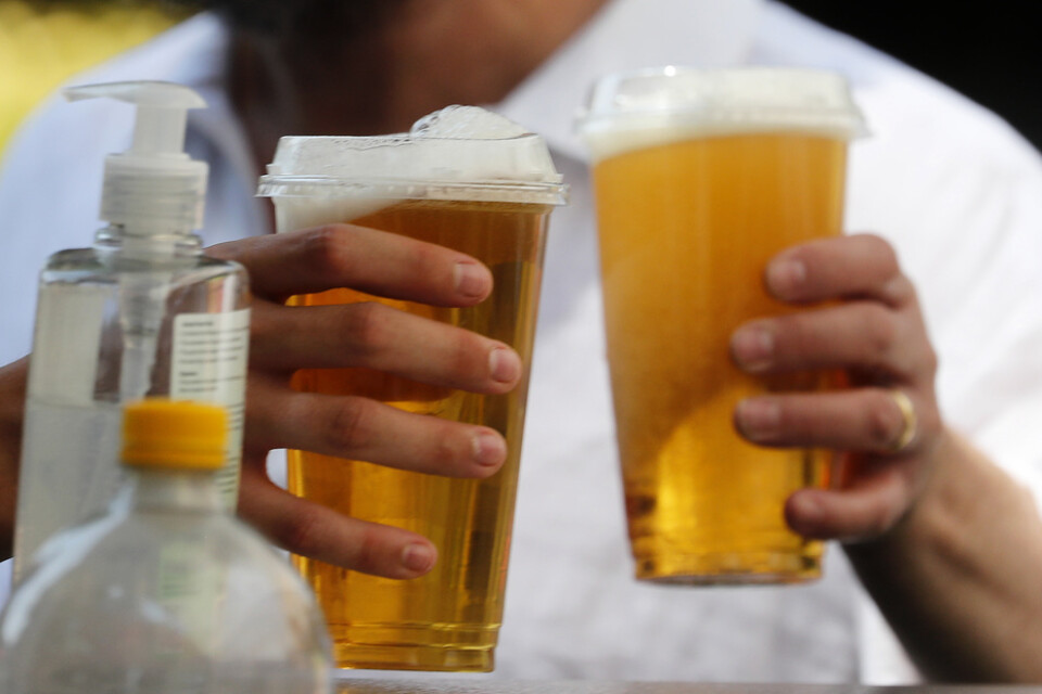 Öl i plastglas att ta med och en flaska handsprit bredvid. Snart kan engelsmännen njuta av en öl inne på en pub igen.
