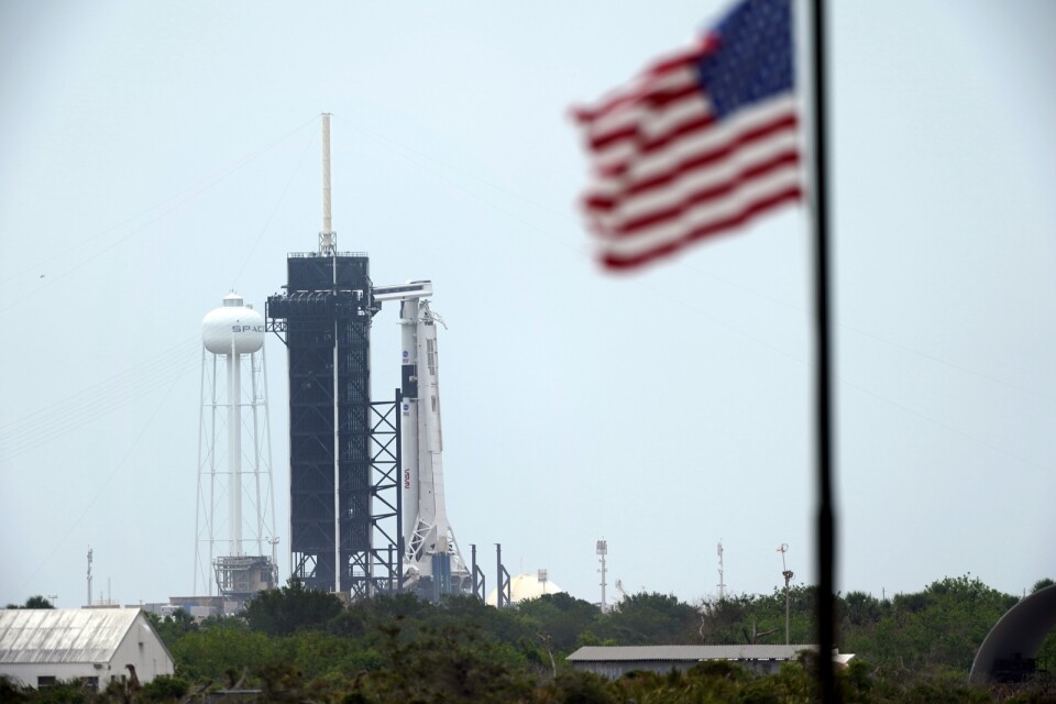 Den startklara Falcon 9-raketen från Space X, med besättningskapseln Crew Dragon högst upp, till höger om det svarta tornet på Kennedy Space Center.