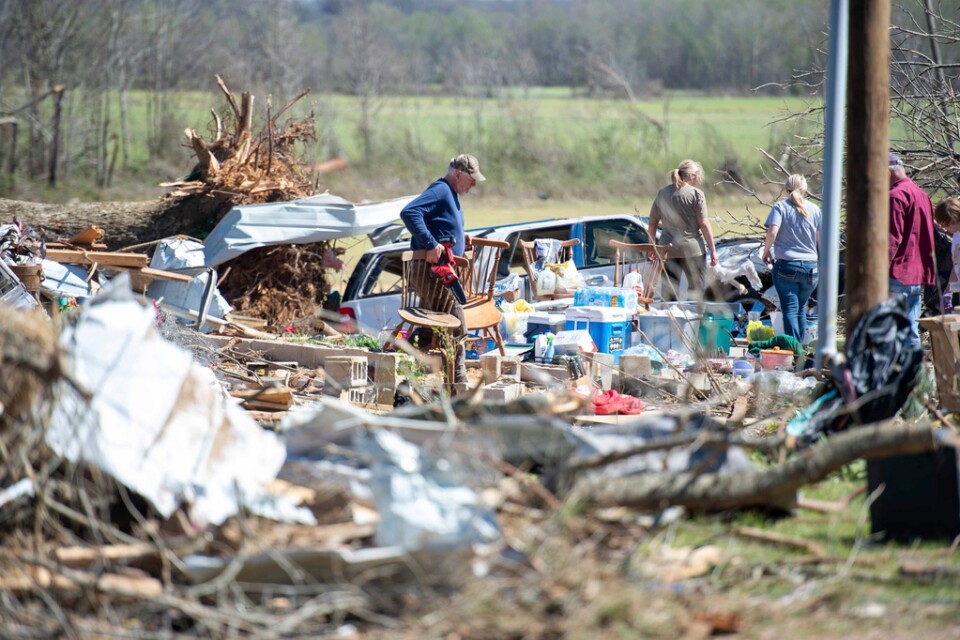 En familj går söker i bråten efter tillhörigheter som går att rädda från ett förstört hem i Adamsville, Tennessee i USA.