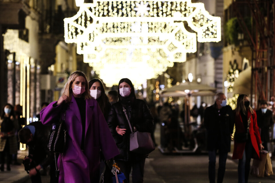 Munskyddsförsedda shoppare på en julpyntad gata i Rom på måndagen.