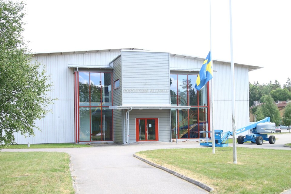 Flaggan på halvstång utanför Allhallen i Borgstena. Olyckan inträffade på andra sidan hallen och liften som syns i bild hade inget med den att göra.