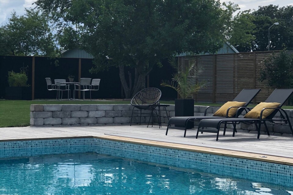 Här ser ni den fantastiska baksidan med pool och trädäck. Trädäcket är inrett med snygga svarta utemöbler. Här njuter familjen till fullo sommartid.