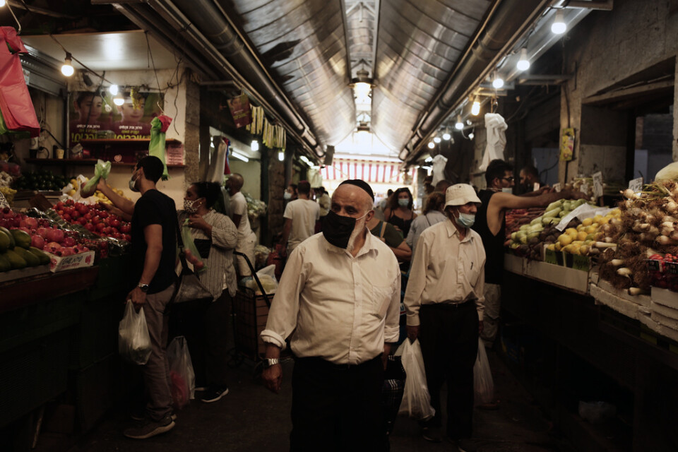 Besökare med mundskydd på Machane Yehuda-marknaden i centrala Jerusalem, timmar innan Israels andra nedstängning träder i kraft.