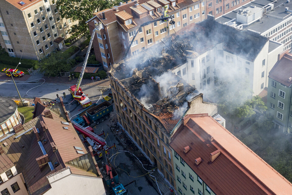 Arbetet efter branden i ett äldre flerfamiljshus i centrala Malmö fortsatte på fredagskvällen. Bit för bit lyfts takkonstruktionen ner för att brandmännen skall komma åt lättare.