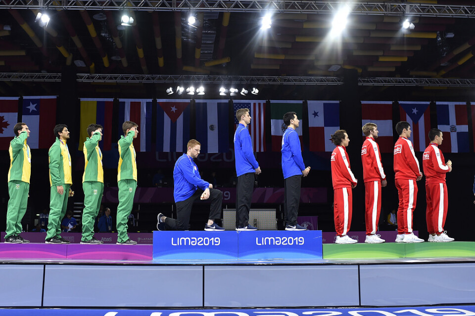 Race Imboden, USA, går ner på knä när den amerikanska nationalsången spelas när lagmedaljerna i florett delas ut vid Panamerikanska spelen i Lima.