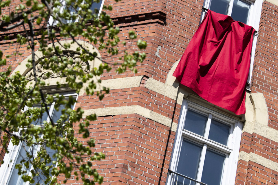 En röd fana hänger från en fransk balkong på ett flerfamiljshus på Möllevångstorget i Malmö på första maj 2020 som också blev digital på grund av pandemin. Arkivbild.