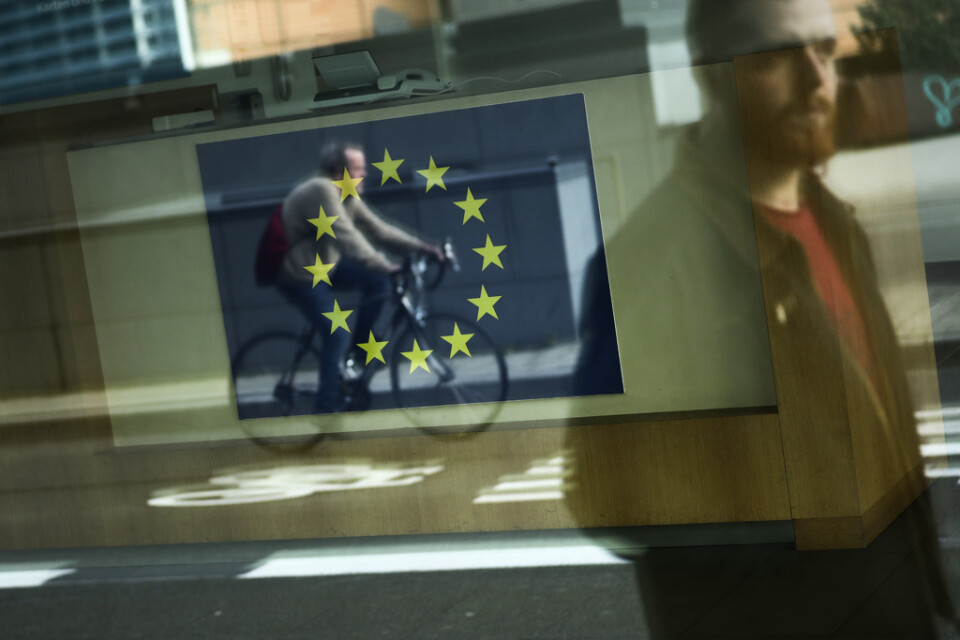Förbipasserande speglas i ett fönster vid EU-kommissionens högkvarter i Bryssel.