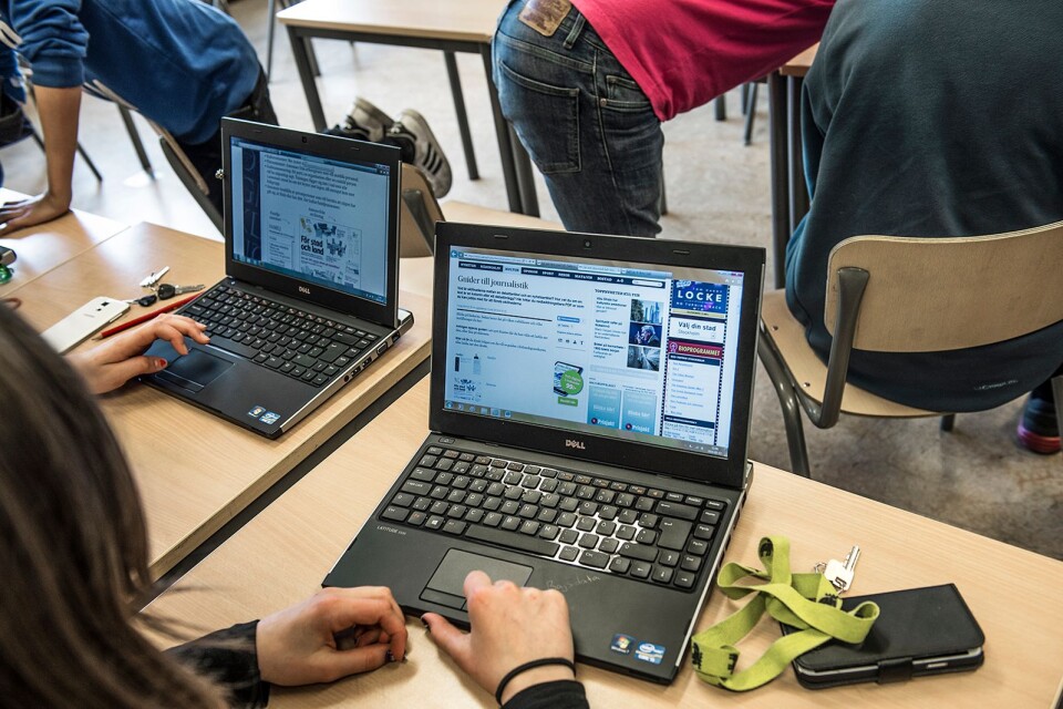 Elever jobbar med datorer i klassrummet.