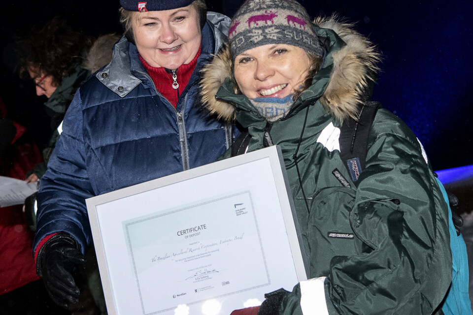 Norges statsminister Erna Solberg delar ut certifikat till Rosa Lía Barbieri från den brasilianska genbanken Embrapa vid tisdagskvällens frödeponeringsceremoni utanför Svalbards globala frövalv i Longyearbyen.