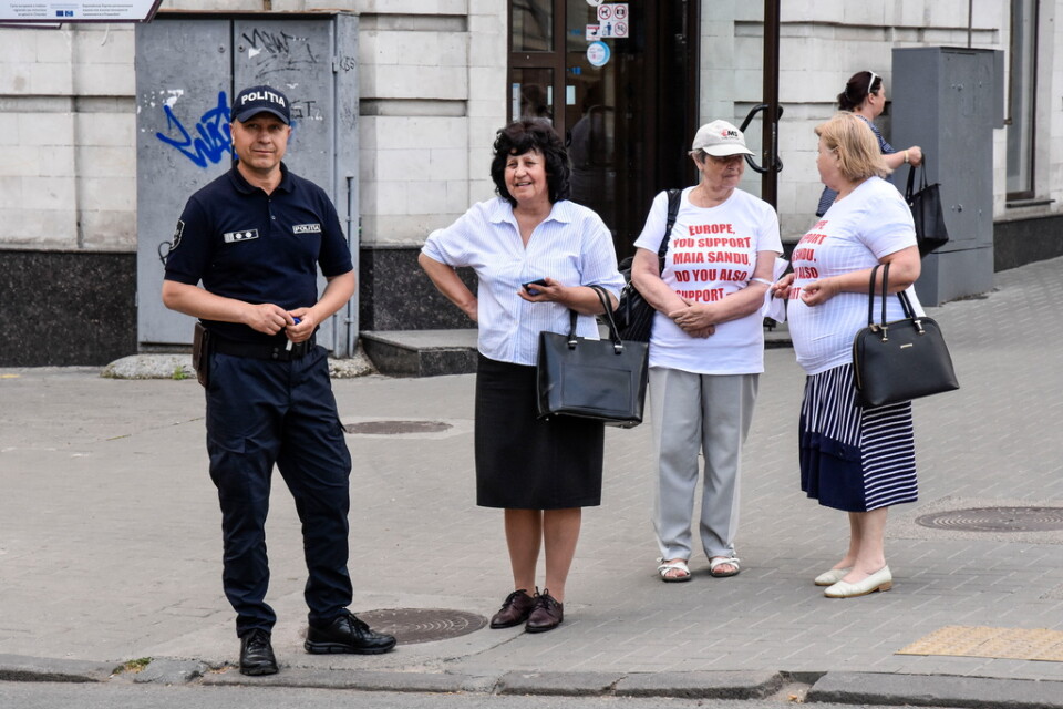 Två damer i vita t-tröjor markerar stillsamt sitt missnöje med Moldaviens västinriktade president Maia Sandu. Tröjorna sponsras av en organisation kopplad till korruptionsanklagade oligarken Vladimir Plahotniuc.