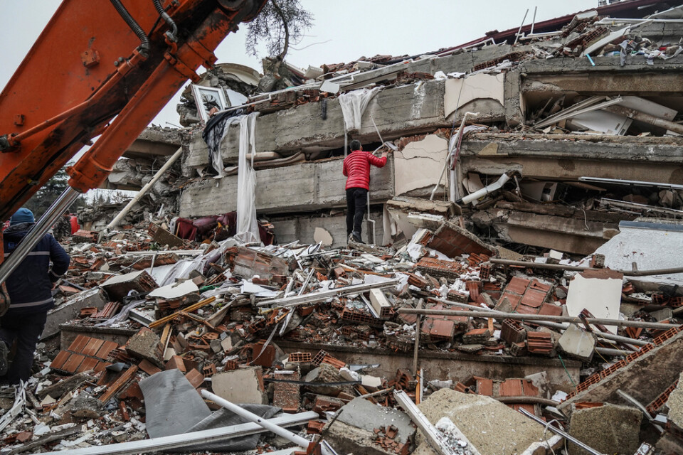 En man letar efter överlevare bland det som finns kvar av en raserad byggnad i Gaziantep.
