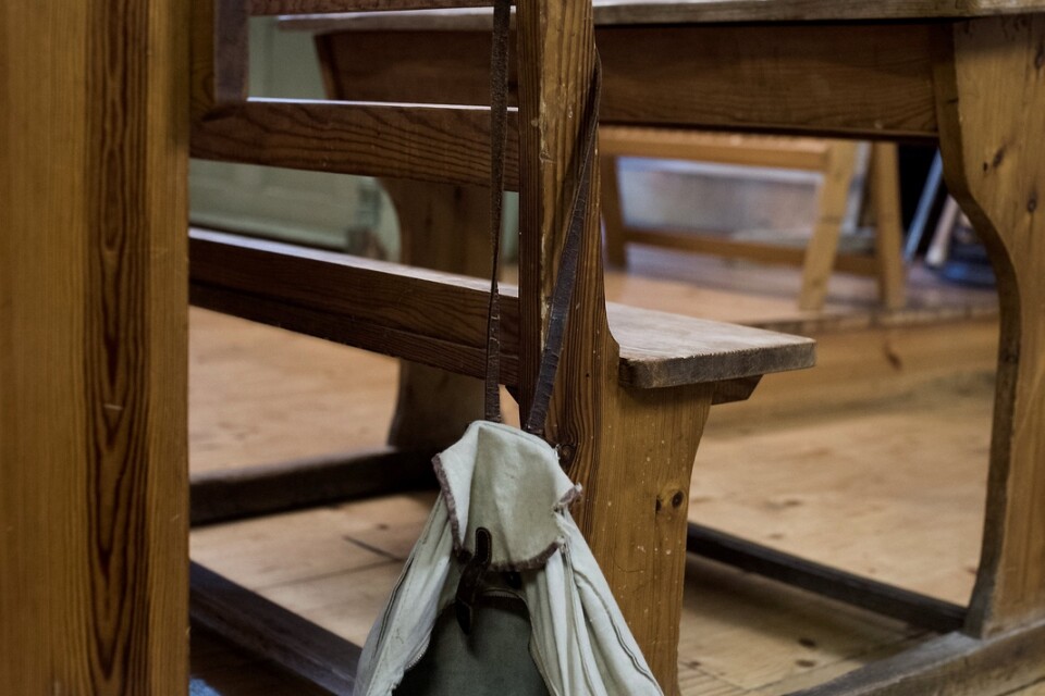 Bjärnumsprofilen Birger Olssons gamla skolväska med matlåda och lärobok hänger på en av de gamla skolbänkarna i Bjärnums museums skolbyggnad.