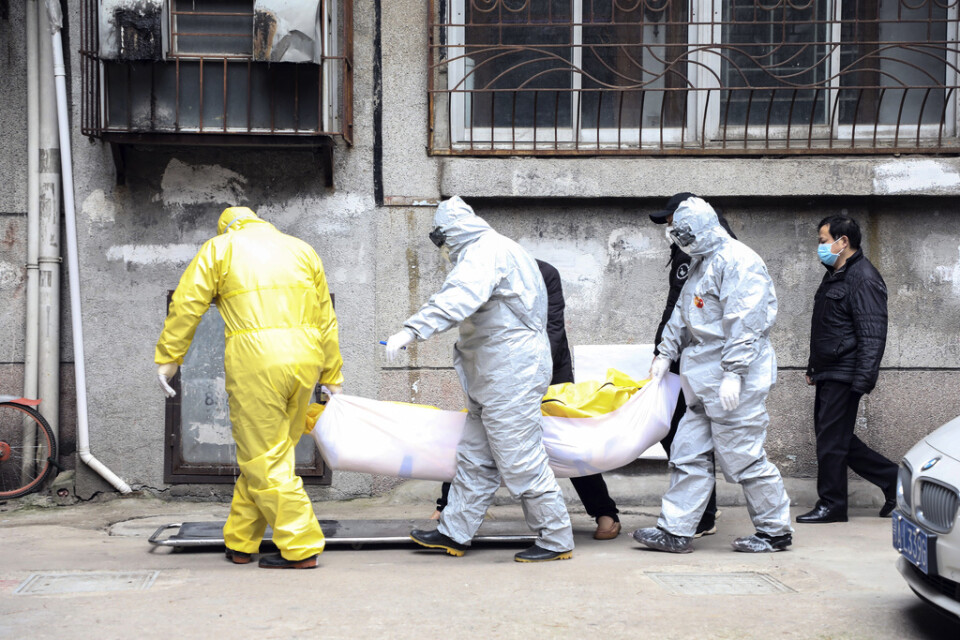 Personal tar hand om en avliden person som misstänks ha dött av viruset i Wuhan. Bild tagen 1 februari.