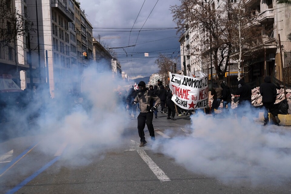 En demonstrant sparkar tillbaka en behållare med tårgas mot kravallpolisen under protesterna i Aten.
