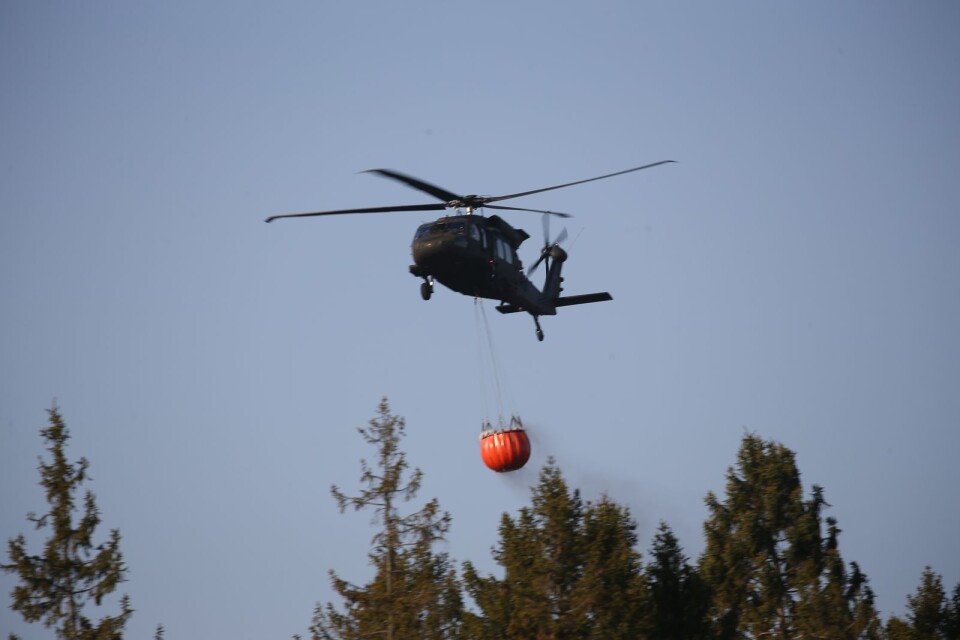 A helicopter water bombs the fire at Hästveda.