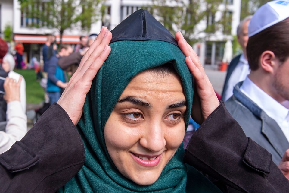 En muslimsk kvinna fäster en kippa ovanpå sin slöja under en demonstration mot antisemitism.