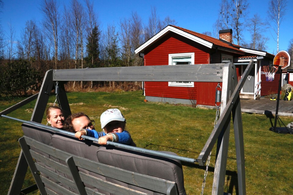 Eva Olsson, Mathias Dahl och sonen Elias Dahl i hammocken framför deras nyinköpta stuga strax ovanför Mogdens strand.