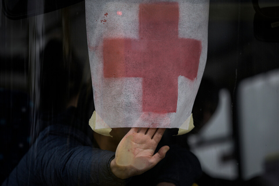 En man håller upp ett rött kors på en buss med civila på väg att evakueras från den ukrainska staden Irpin.